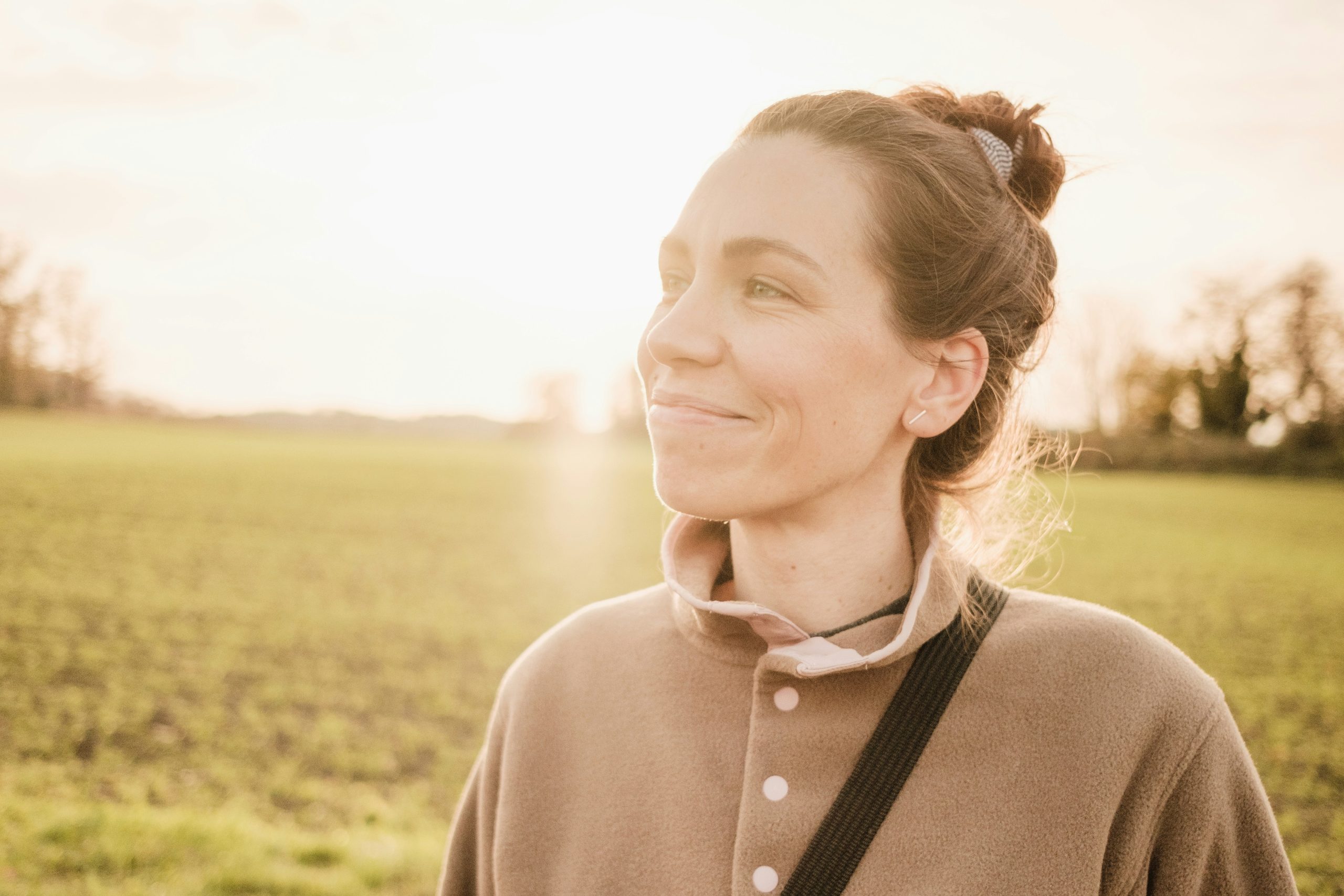 Woman in her 40s sitting by a window in soft morning light, looking calm and thoughtful
