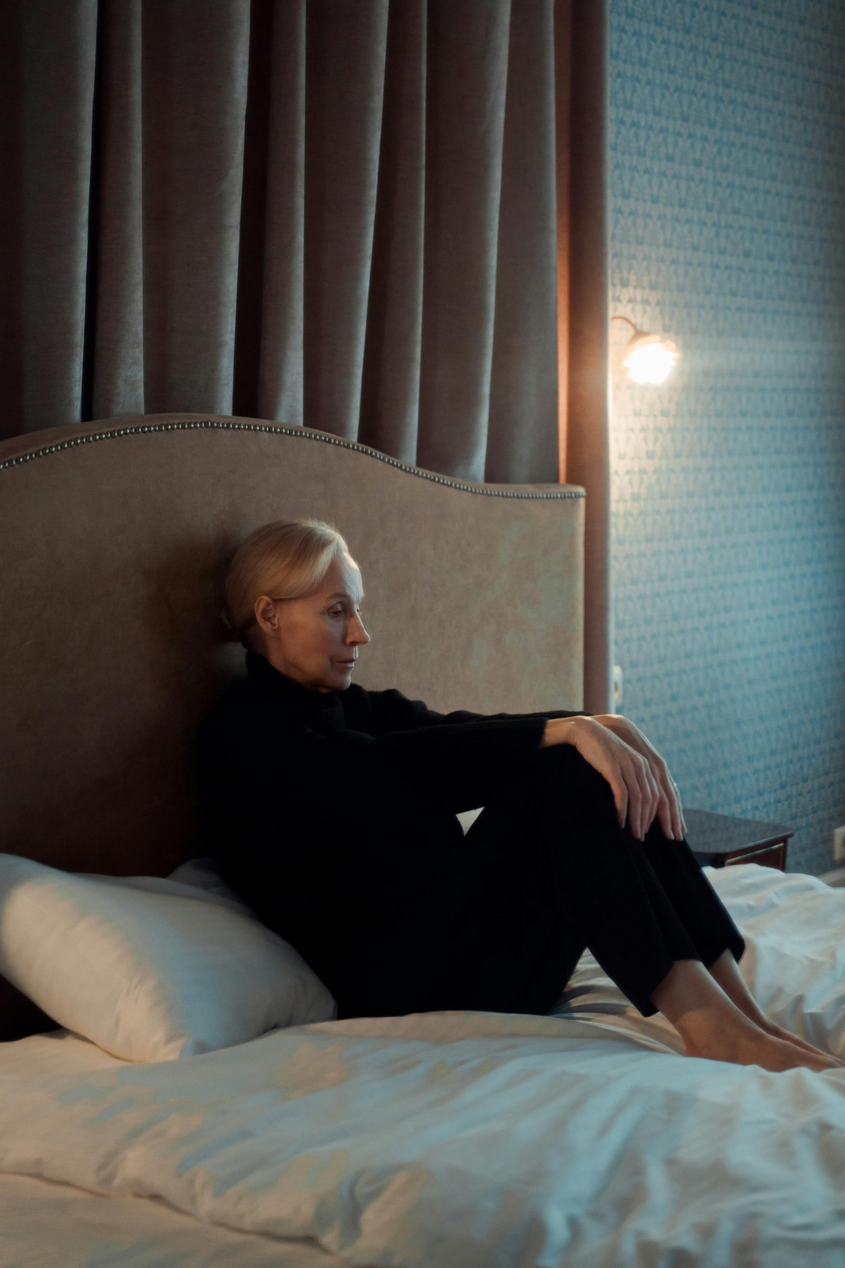 Woman in her 40s sitting alone, pensive and thoughtful, in warm soft light